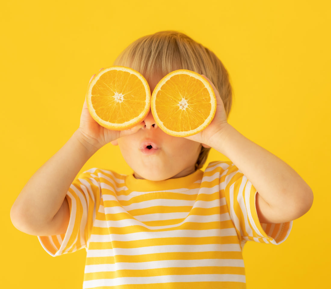 Un enfant heureux qui tiens des oranges devant ses yeux