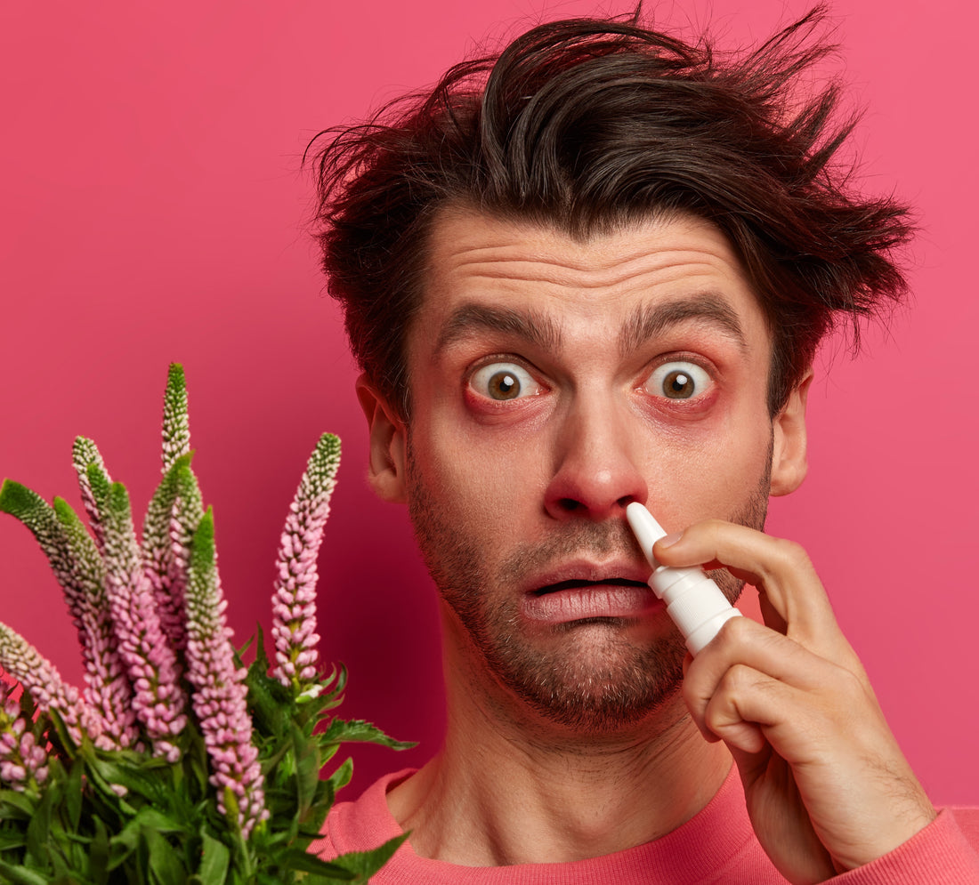 Un homme avec les yeux et le nez rouge, qui a des allergies à cause d'un bouquet de fleurs