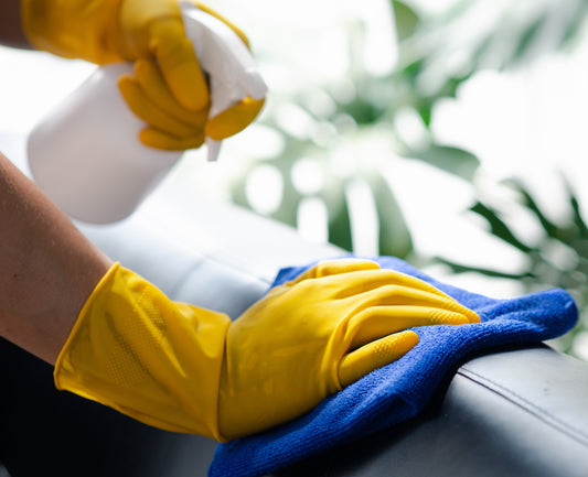 Quelqu'un qui utilise un produit de nettoyage avec des gants jaunes et une lavette bleu